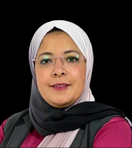 A woman wearing a hijab and glasses, sitting in front of a dark background.